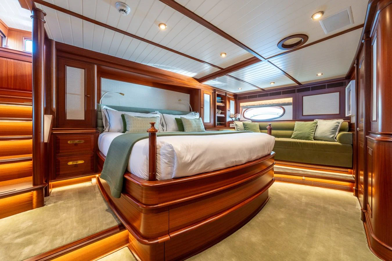 The master stateroom features a luxurious bed, elegant wood paneling, and ambient lighting. aboard ATHOS Yacht for Sale