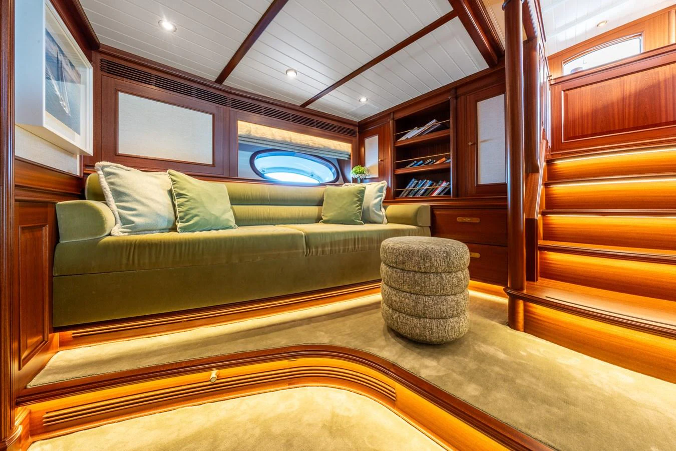 The salon features a cozy seating area with plush cushions and warm wood accents, illuminated by soft ambient lighting. aboard ATHOS Yacht for Sale