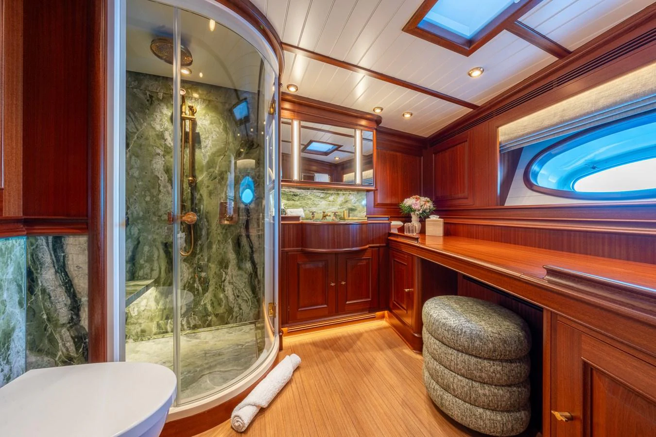 The yacht's bathroom features luxurious wood paneling and a spacious shower with marble accents. aboard ATHOS Yacht for Sale