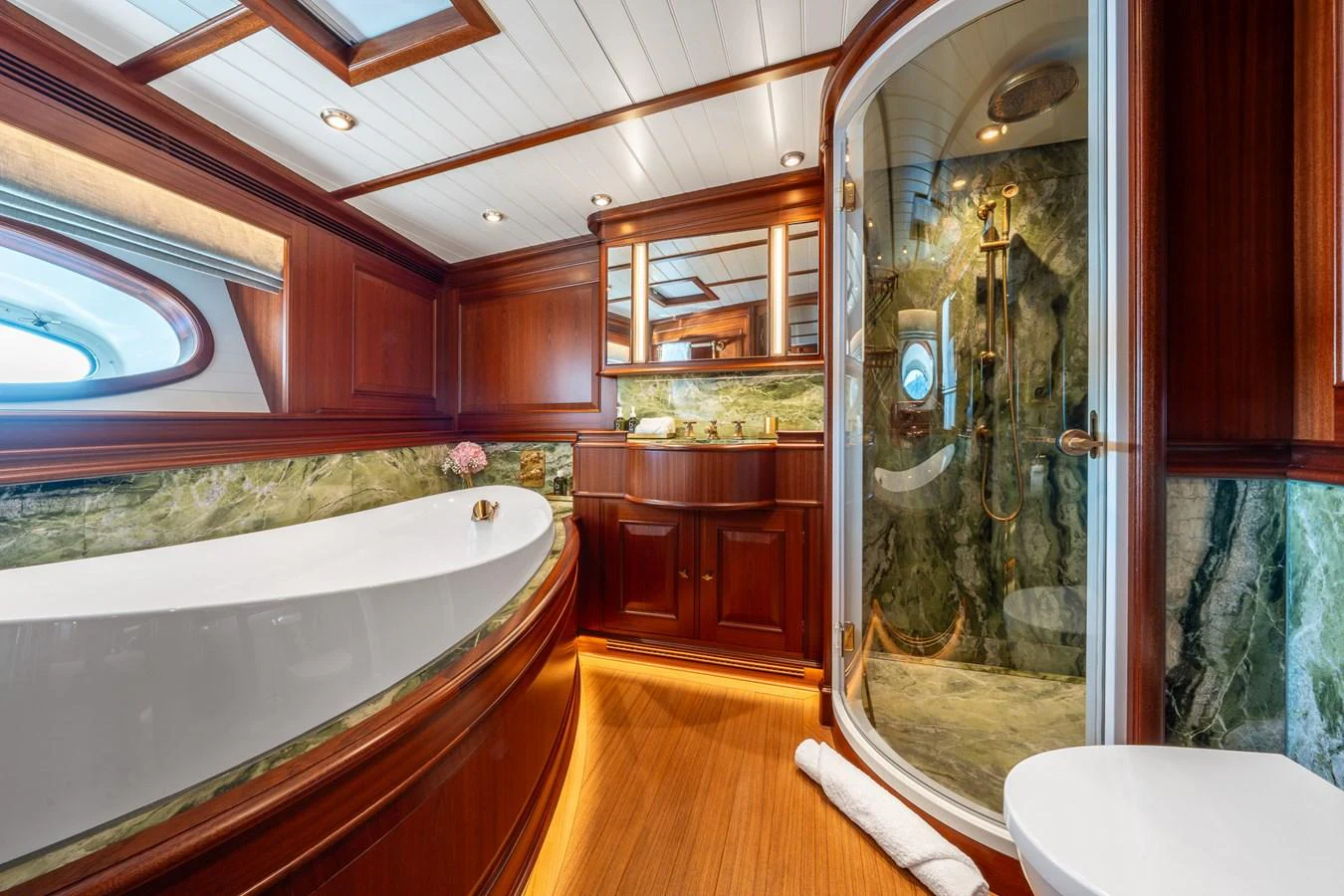 The yacht's bathroom features luxurious wood paneling, a spacious bathtub, and a glass-enclosed shower. aboard ATHOS Yacht for Sale