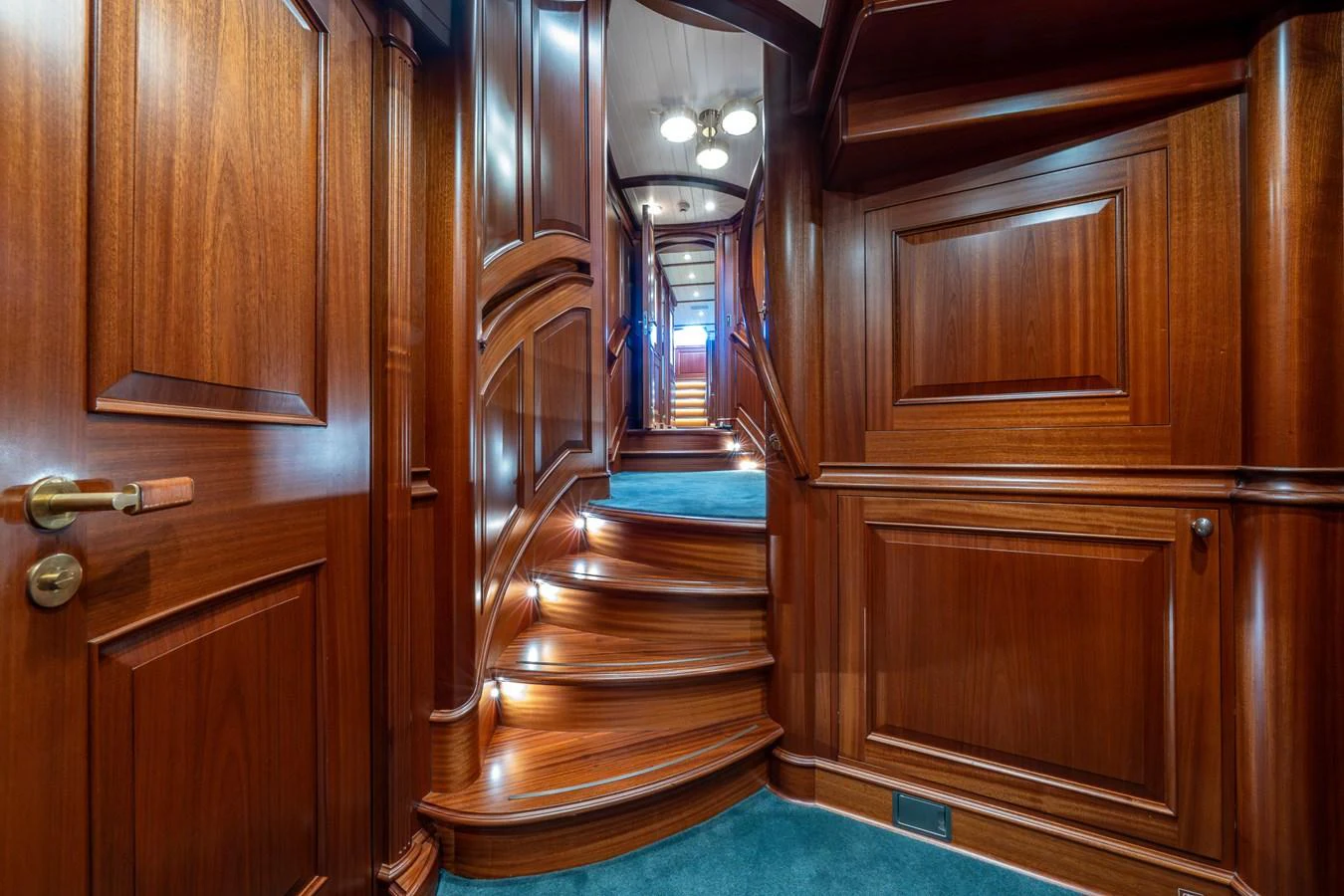 A luxurious wooden hallway with carpeted stairs leading to the upper deck. aboard ATHOS Yacht for Sale