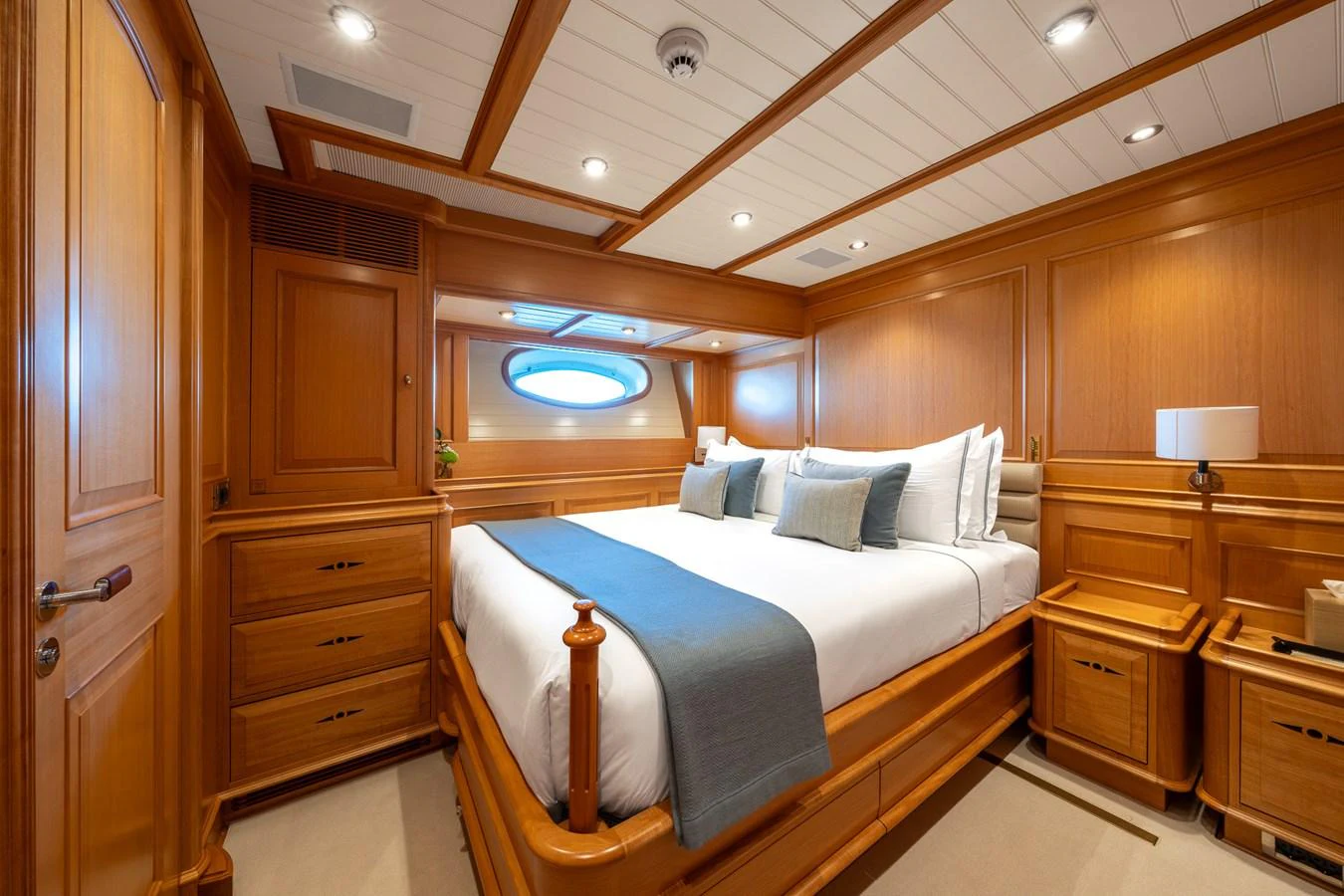 The stateroom features a luxurious bed with elegant wooden paneling and ample lighting. aboard ATHOS Yacht for Sale