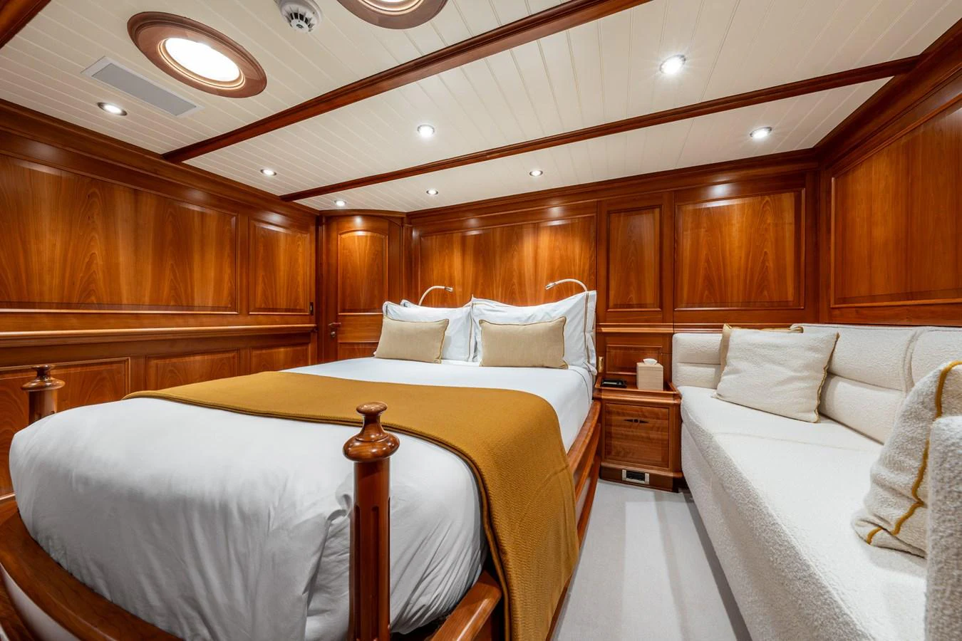 The stateroom features elegant wood paneling and luxurious bedding, creating a warm and inviting atmosphere. aboard ATHOS Yacht for Sale