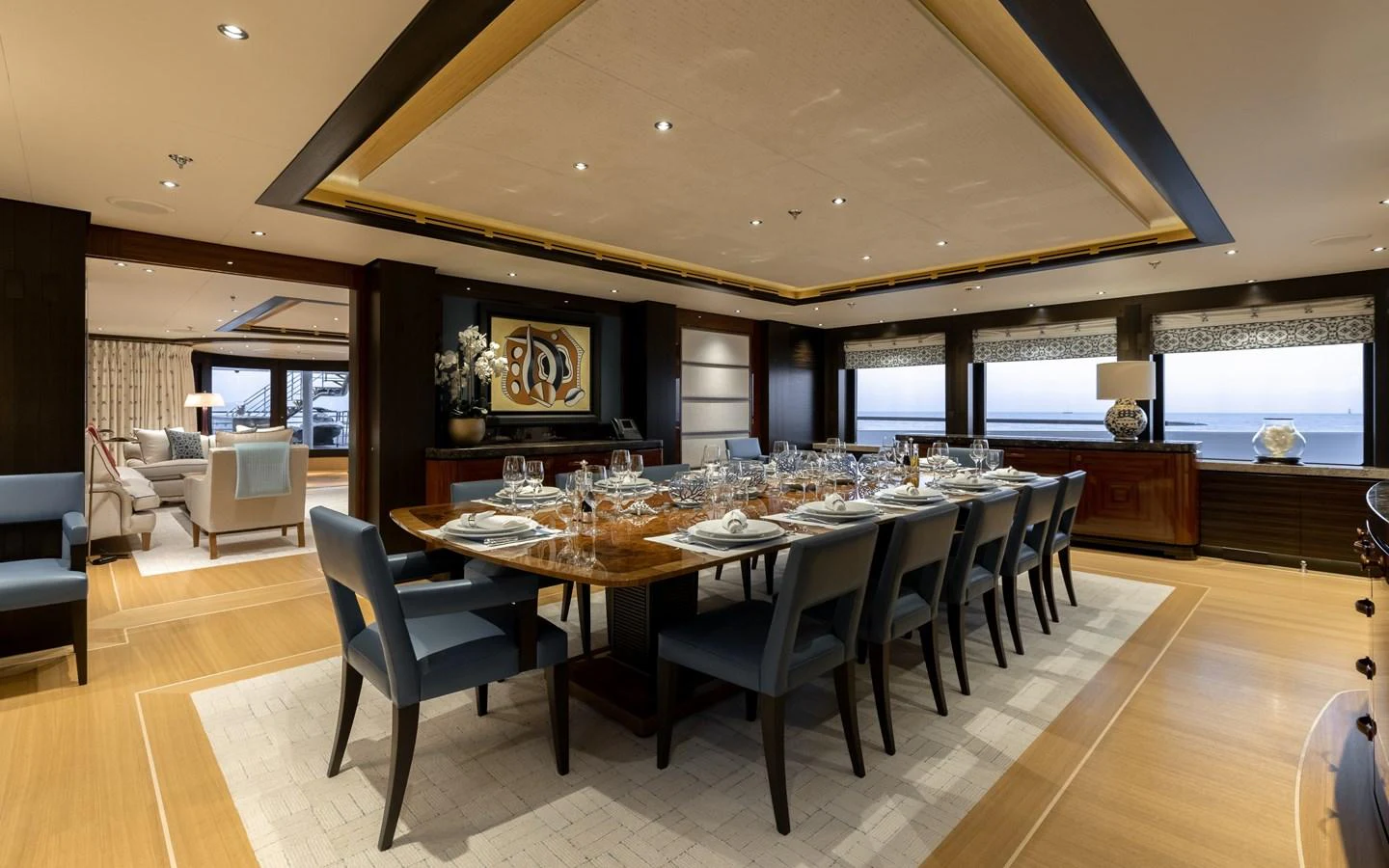 The yacht's dining area features an elegant table set for a formal meal, surrounded by plush seating and warm lighting. aboard BATON ROUGE Yacht for Sale