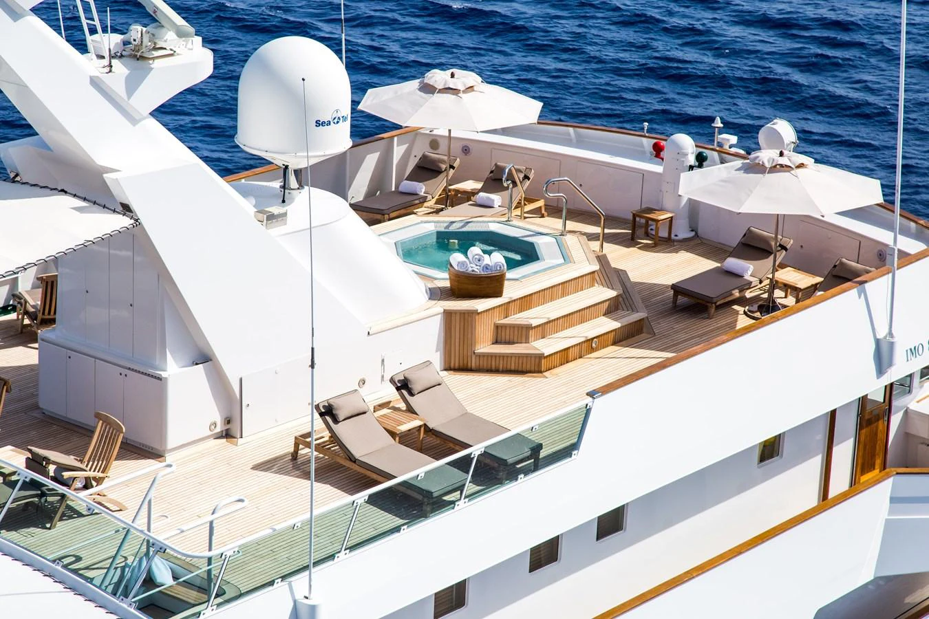 The sundeck features a luxurious jacuzzi surrounded by sun loungers and parasols, offering a perfect spot for relaxation. aboard ESMERALDA Yacht for Sale