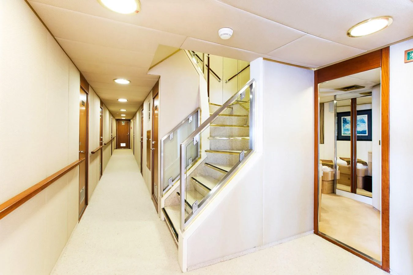 The image showcases a well-lit hallway with a staircase leading to another level inside the yacht. aboard ESMERALDA Yacht for Sale