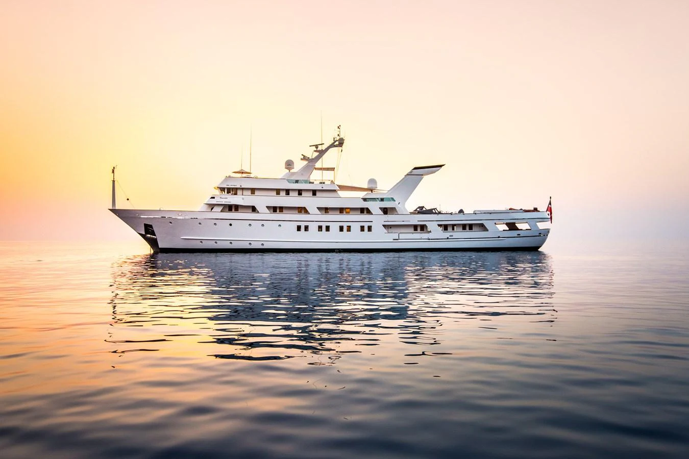 A stunning yacht is gracefully anchored on calm waters during a serene sunset. aboard ESMERALDA Yacht for Sale