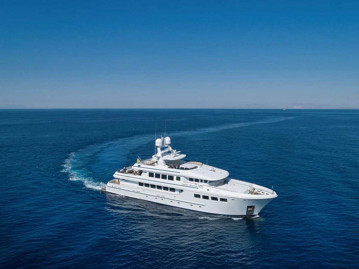 A luxurious yacht cruising through the open sea under a clear blue sky. aboard HAPPY DOLPHIN II Yacht for Sale