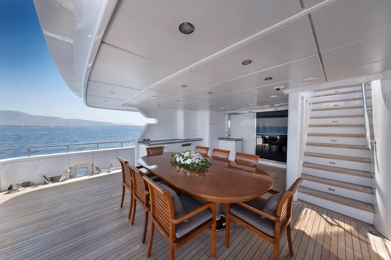 The aft deck features a spacious dining area with a polished wooden table and comfortable chairs, perfect for al fresco dining with a view of the sea. aboard HAPPY DOLPHIN II Yacht for Sale