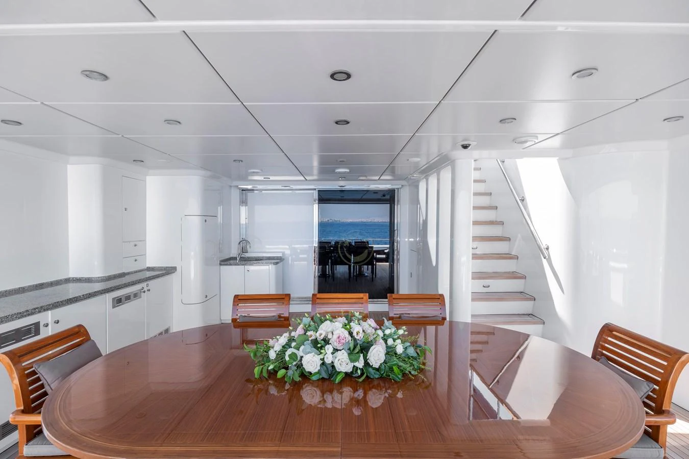 The yacht's interior dining area features a polished wooden table with a floral centerpiece, surrounded by elegant seating. aboard HAPPY DOLPHIN II Yacht for Sale