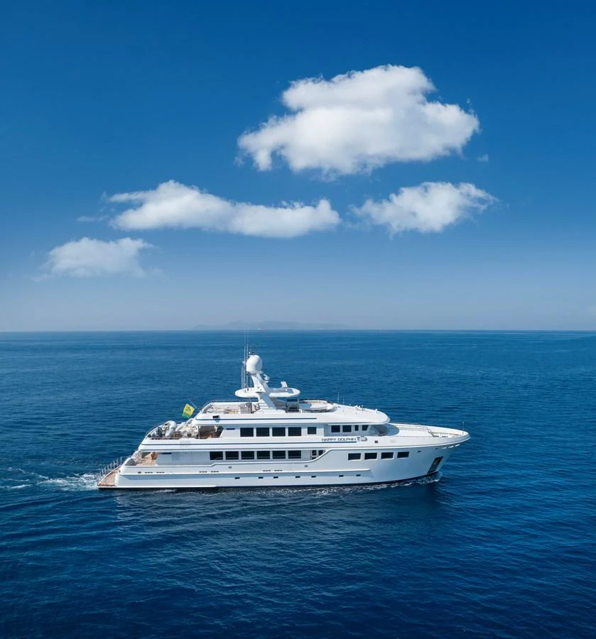 A luxurious yacht cruising through calm blue waters under a clear sky. aboard HAPPY DOLPHIN II Yacht for Sale
