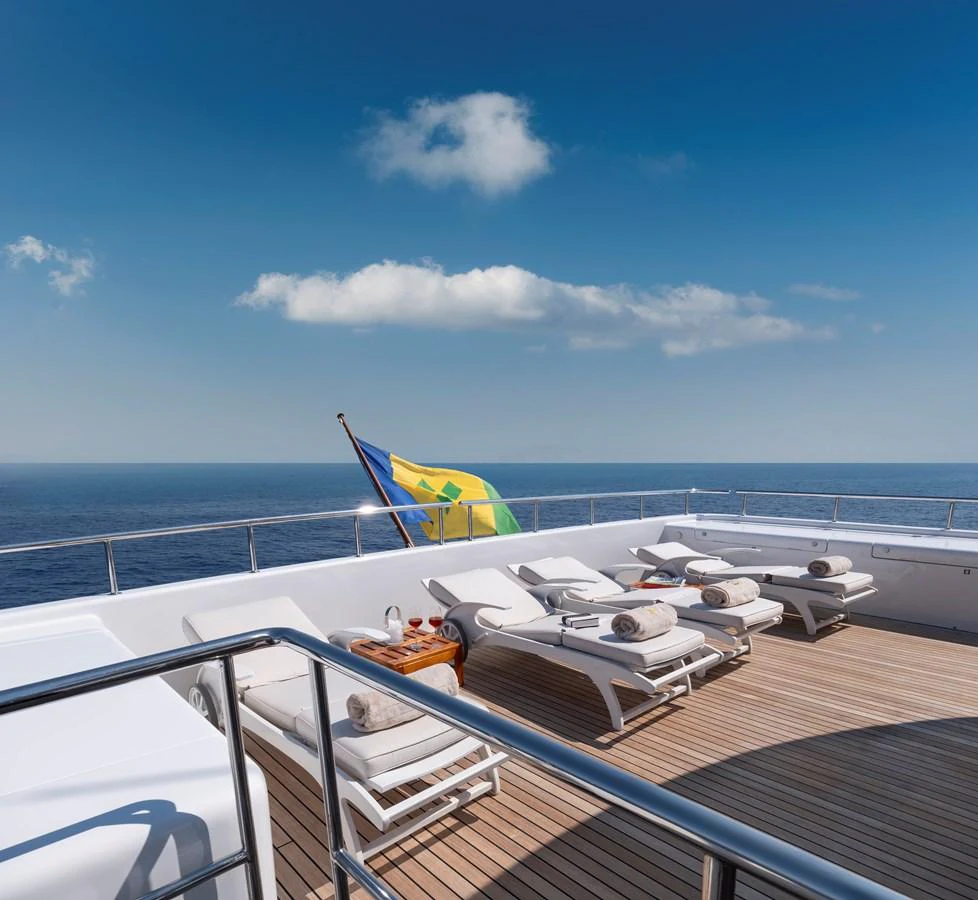 The sundeck offers a serene space with luxurious sun loungers and a stunning ocean view. aboard HAPPY DOLPHIN II Yacht for Sale