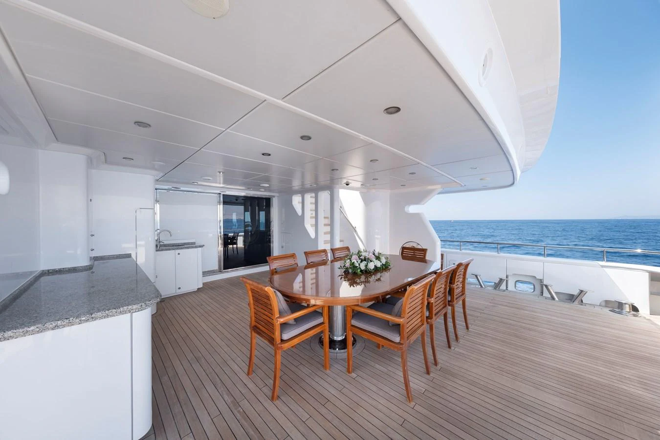 The aft deck features a spacious dining area with a polished wooden table and comfortable chairs, perfect for al fresco meals with a view of the sea. aboard HAPPY DOLPHIN II Yacht for Sale