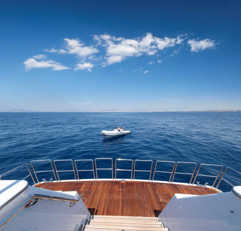 The yacht's aft deck offers a stunning view of the open sea with a tender in the distance. aboard HAPPY DOLPHIN II Yacht for Sale