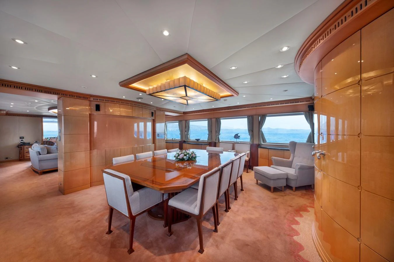 The yacht's dining area features a large wooden table surrounded by plush chairs, offering a luxurious setting for meals with panoramic ocean views. aboard HAPPY DOLPHIN II Yacht for Sale