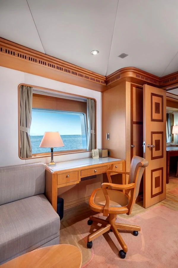 A cozy stateroom with a desk, chair, and a window offering a sea view. aboard HAPPY DOLPHIN II Yacht for Sale