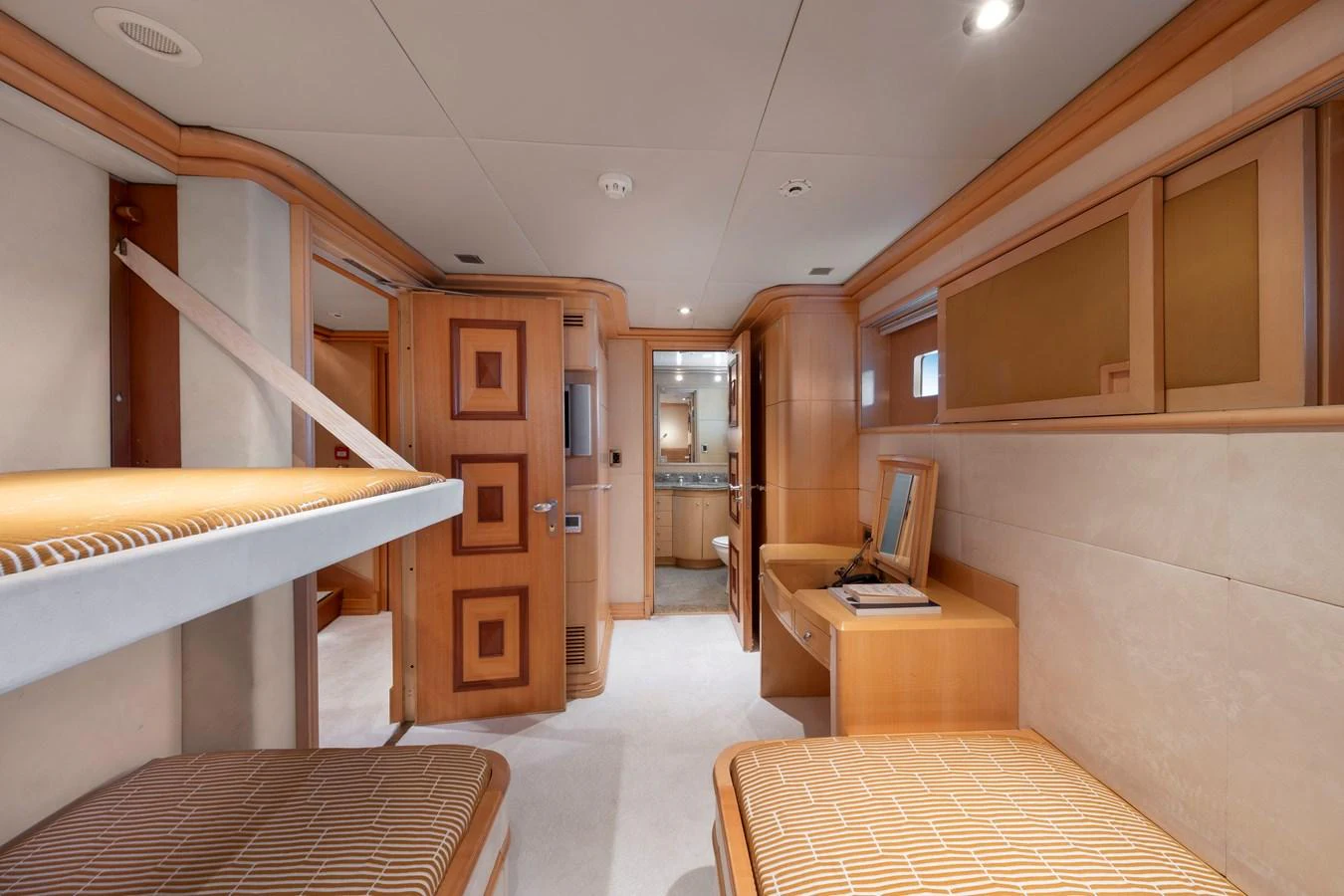 The guest cabin features twin beds and a warm, inviting decor with ample storage and a vanity area. aboard HAPPY DOLPHIN II Yacht for Sale