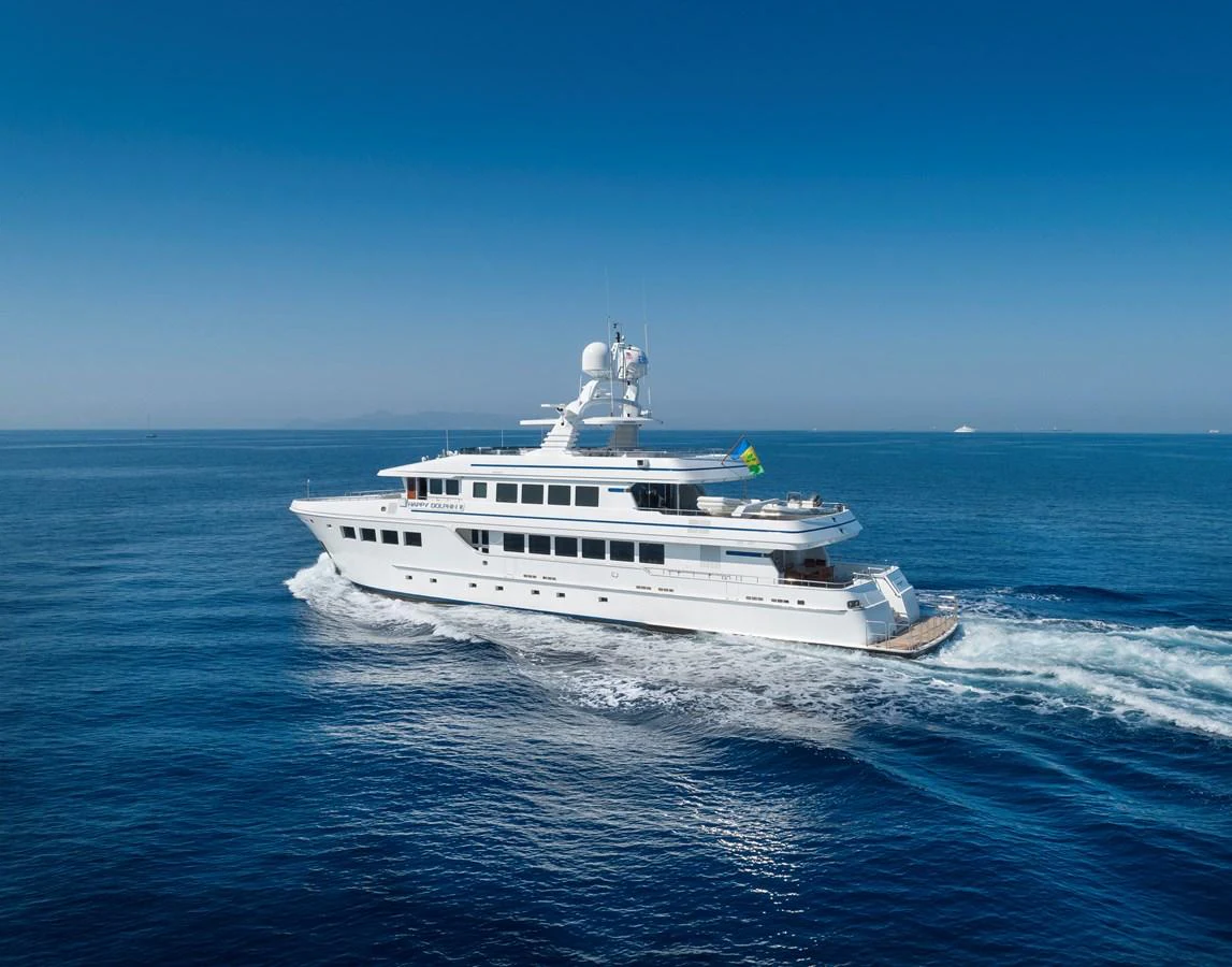 A luxurious yacht cruises through the open sea under a clear blue sky. aboard HAPPY DOLPHIN II Yacht for Sale