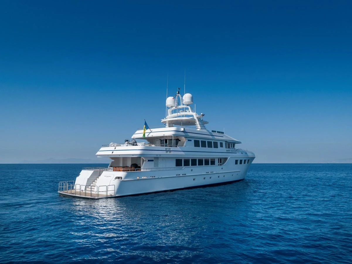 A luxurious yacht cruises on calm, clear blue waters under a bright blue sky. aboard HAPPY DOLPHIN II Yacht for Sale
