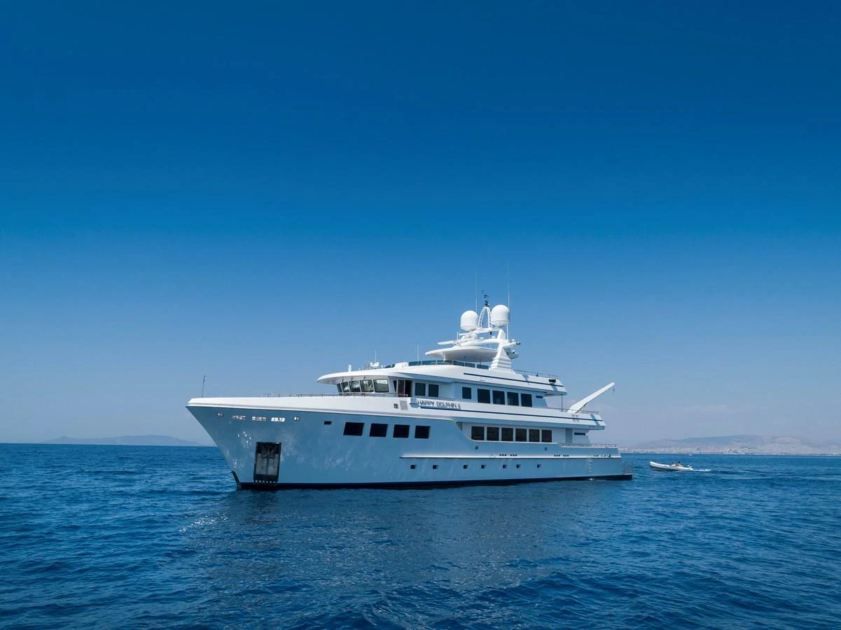 A sleek and elegant yacht glides gracefully on the open sea under a clear blue sky. aboard HAPPY DOLPHIN II Yacht for Sale
