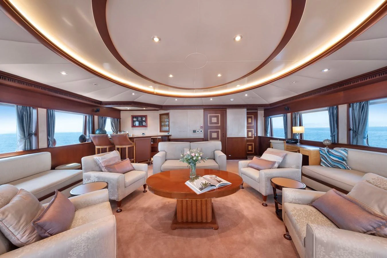The spacious salon features elegant seating and panoramic windows with ocean views. aboard HAPPY DOLPHIN II Yacht for Sale