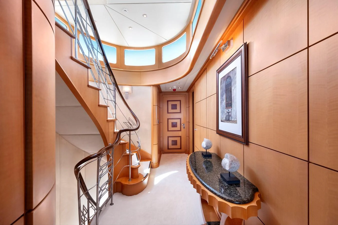 The yacht's interior features a beautifully designed staircase with elegant wood paneling and modern decor. aboard HAPPY DOLPHIN II Yacht for Sale