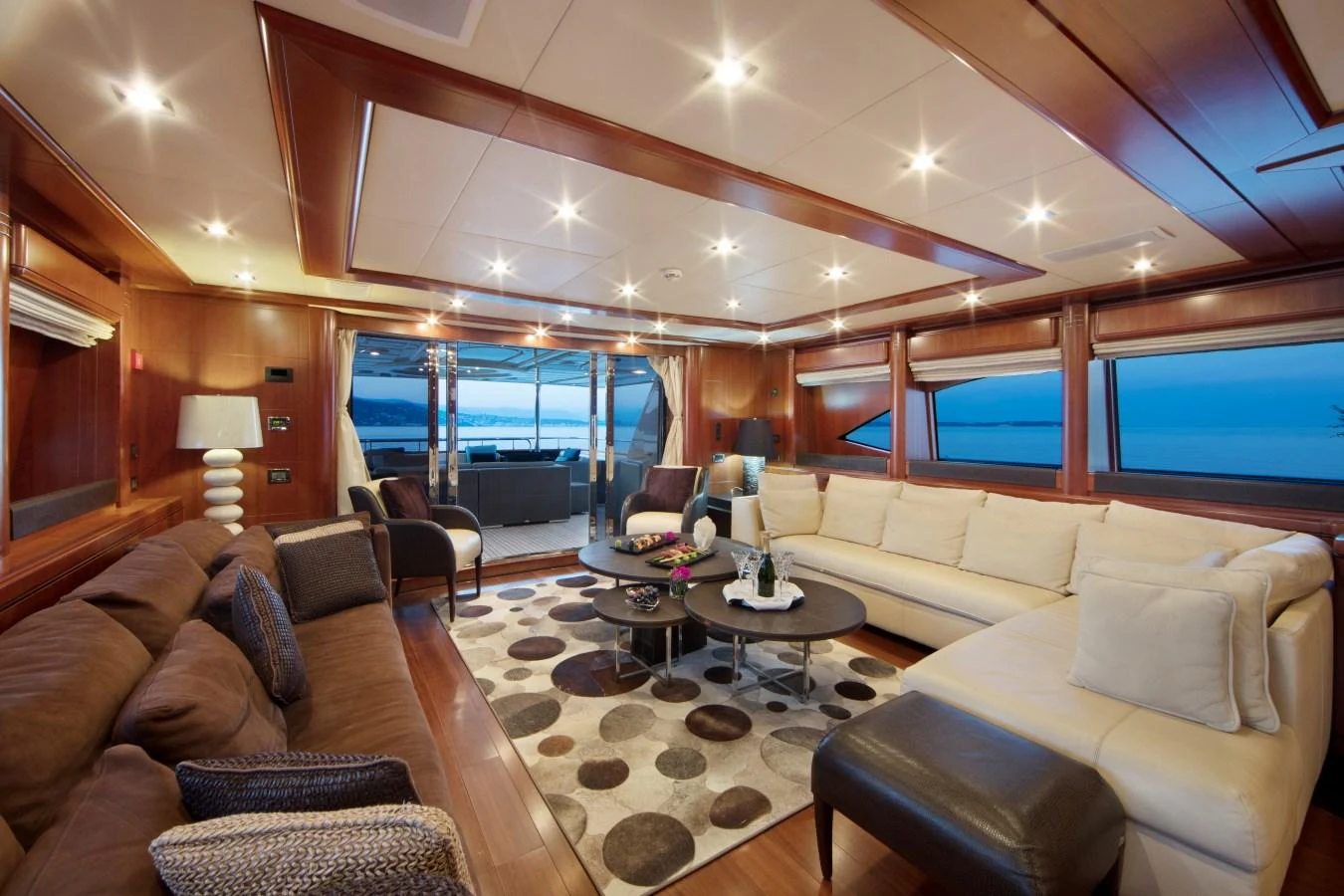 The salon features luxurious seating with a view of the aft deck and ocean beyond. aboard SIMA Yacht for Sale