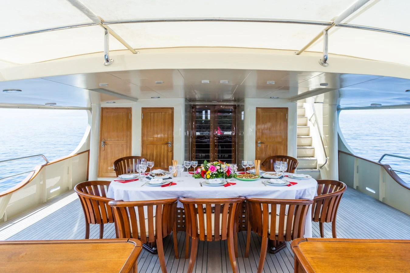 The aft deck features an elegant dining area with a beautifully set table and wooden chairs, perfect for alfresco dining. aboard MESERRET Yacht for Sale