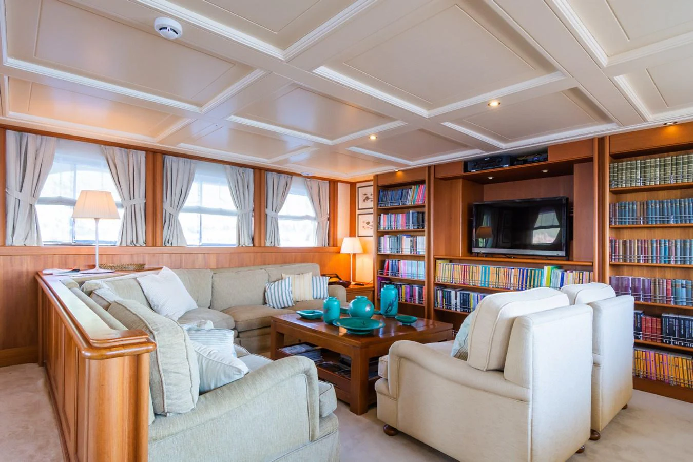 The yacht's salon features a cozy seating area with plush sofas and a well-stocked bookshelf, creating a warm and inviting atmosphere. aboard MESERRET Yacht for Sale