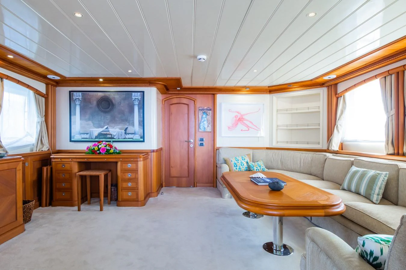 The salon features a cozy seating area with a large sofa and a wooden table, complemented by elegant decor and ample natural light. aboard MESERRET Yacht for Sale