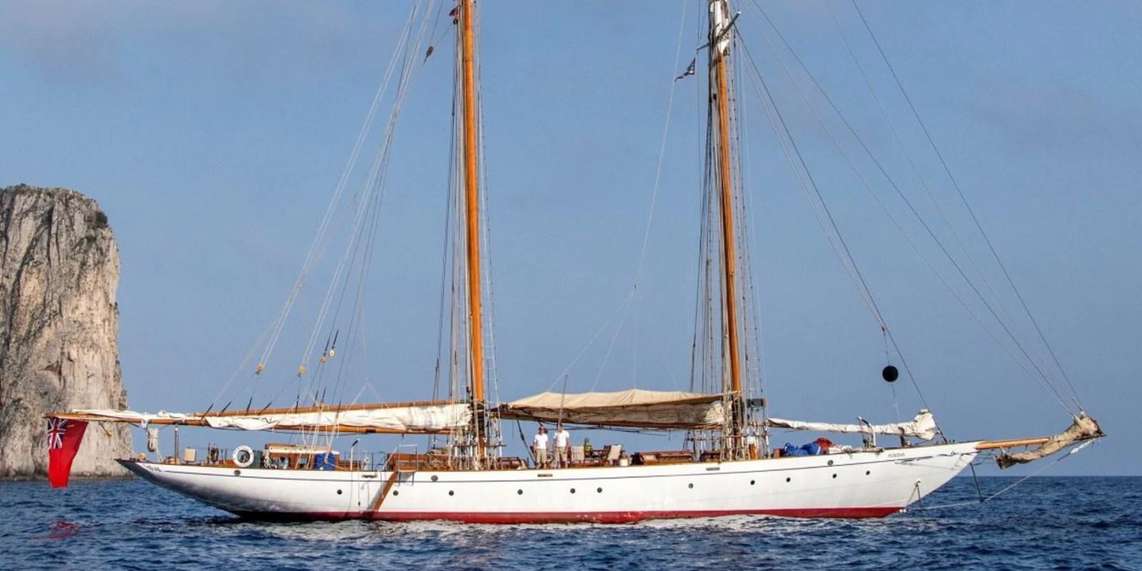 A classic sailing yacht with twin masts glides gracefully on the open sea. aboard PURITAN Yacht for Sale