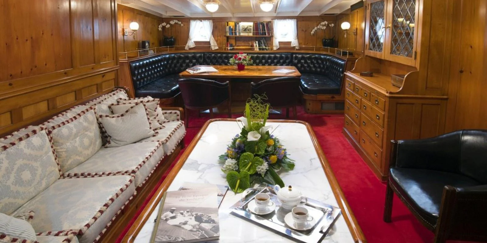 The salon features elegant wood paneling, plush seating, and a cozy dining area, creating a warm and inviting atmosphere. aboard PURITAN Yacht for Sale
