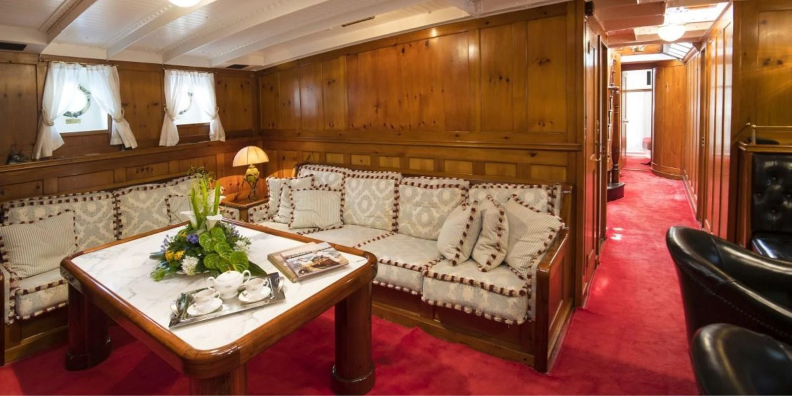 The yacht's interior features a cozy lounge area with wooden paneling and plush seating. aboard PURITAN Yacht for Sale