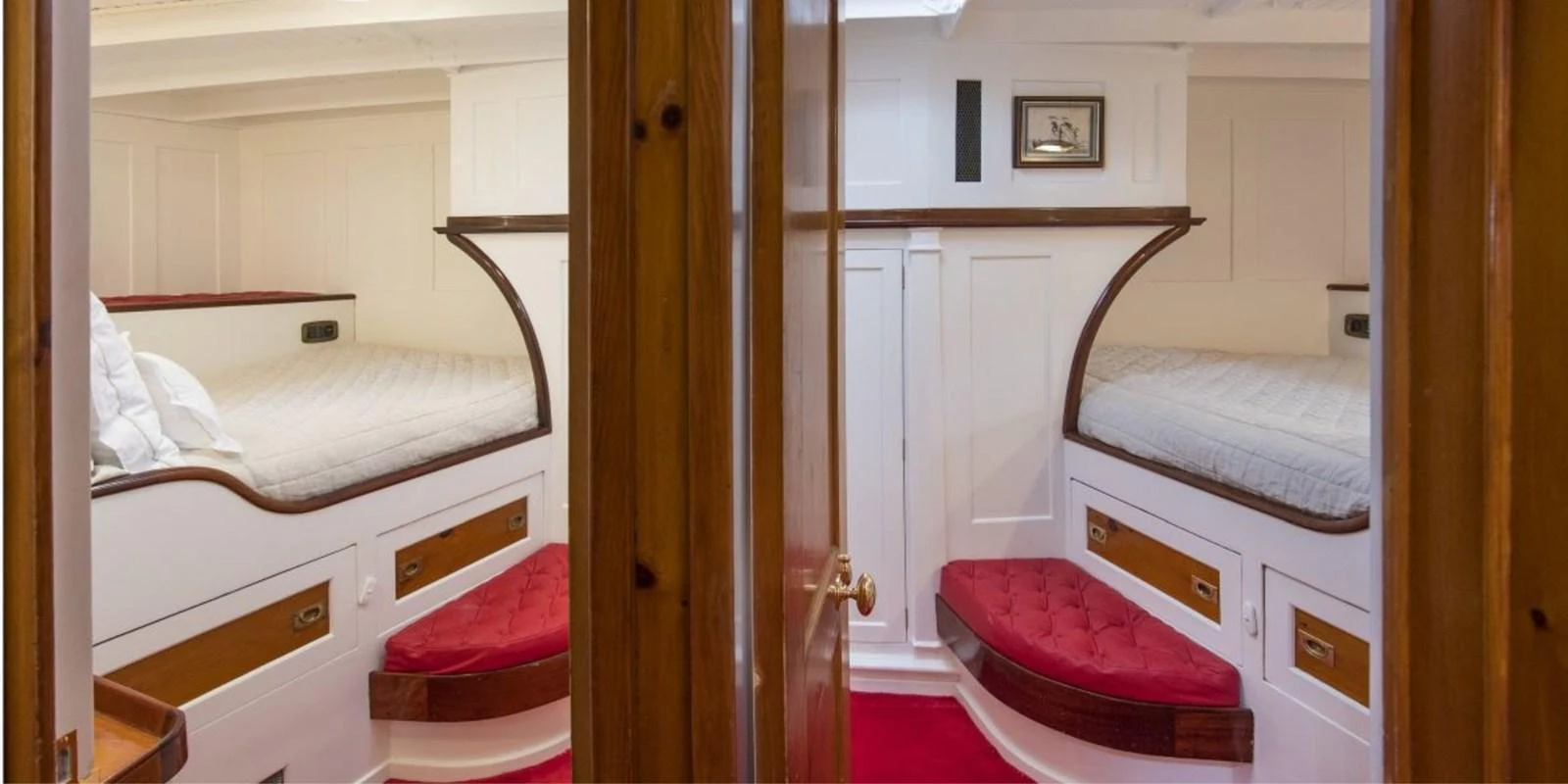 The guest cabin features twin beds with red cushioned seating and wooden accents. aboard PURITAN Yacht for Sale