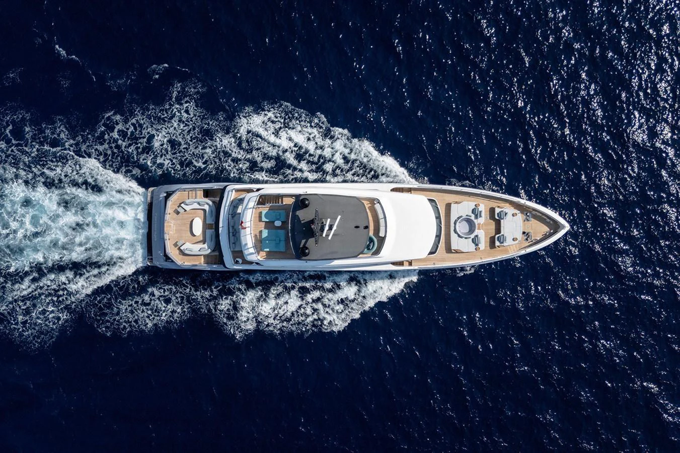 A stunning aerial view of a luxurious yacht cruising through deep blue waters. aboard TAMANYA Yacht for Sale