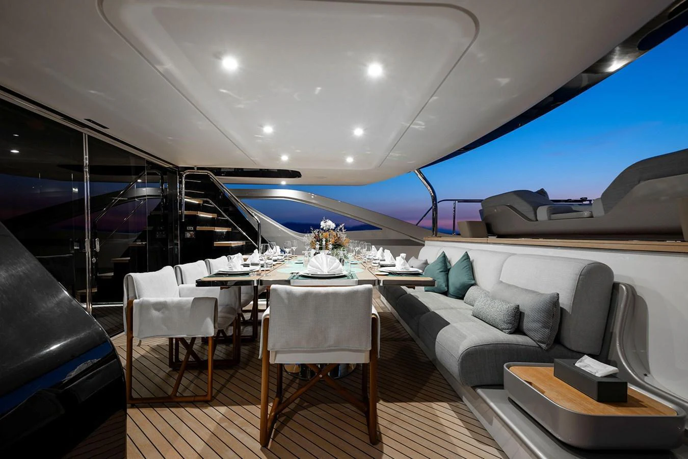 The aft deck features an elegant dining area with a beautifully set table and comfortable seating, perfect for alfresco dining. aboard TAMANYA Yacht for Sale