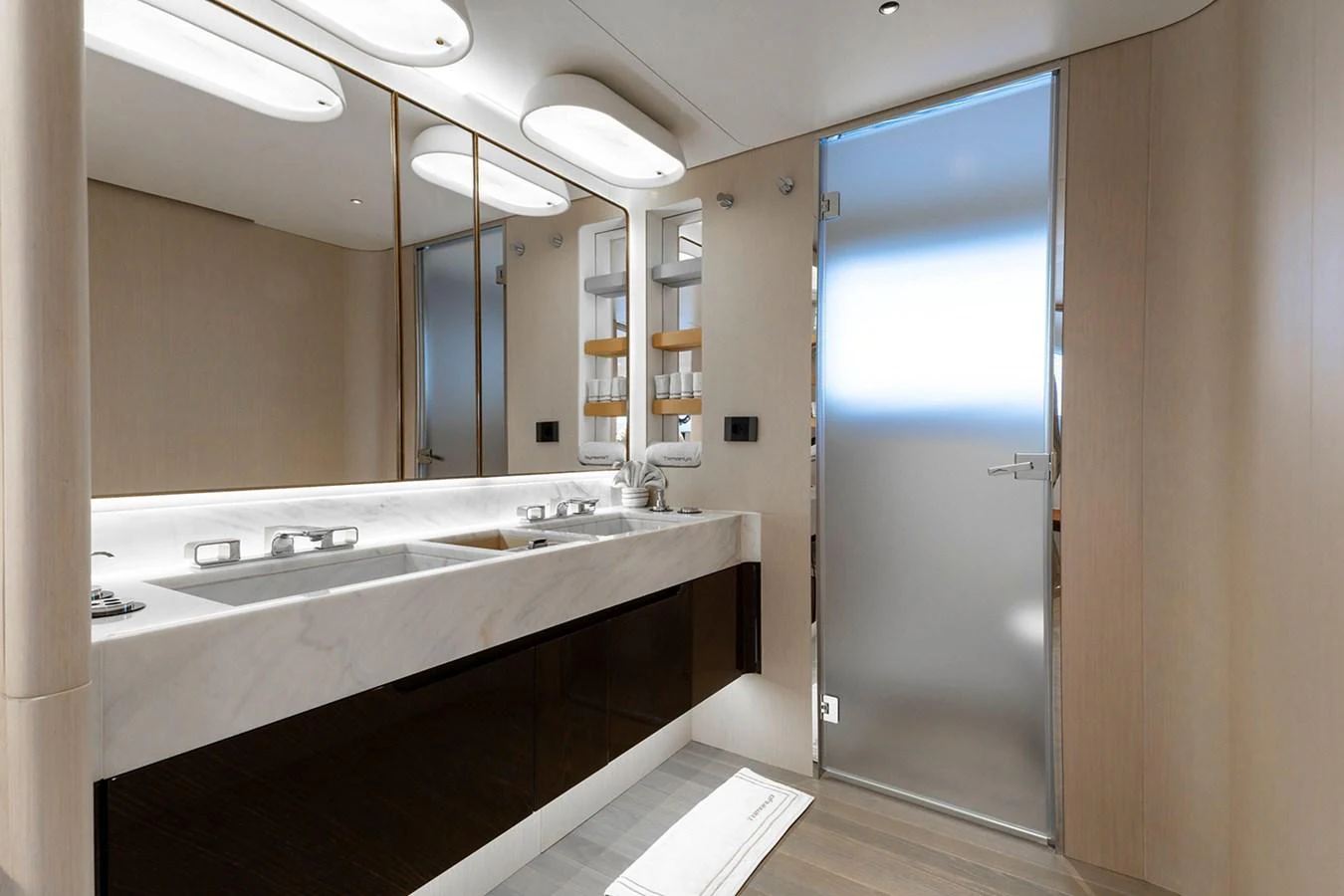 The bathroom features a sleek, modern design with a double sink and frosted glass door. aboard TAMANYA Yacht for Sale