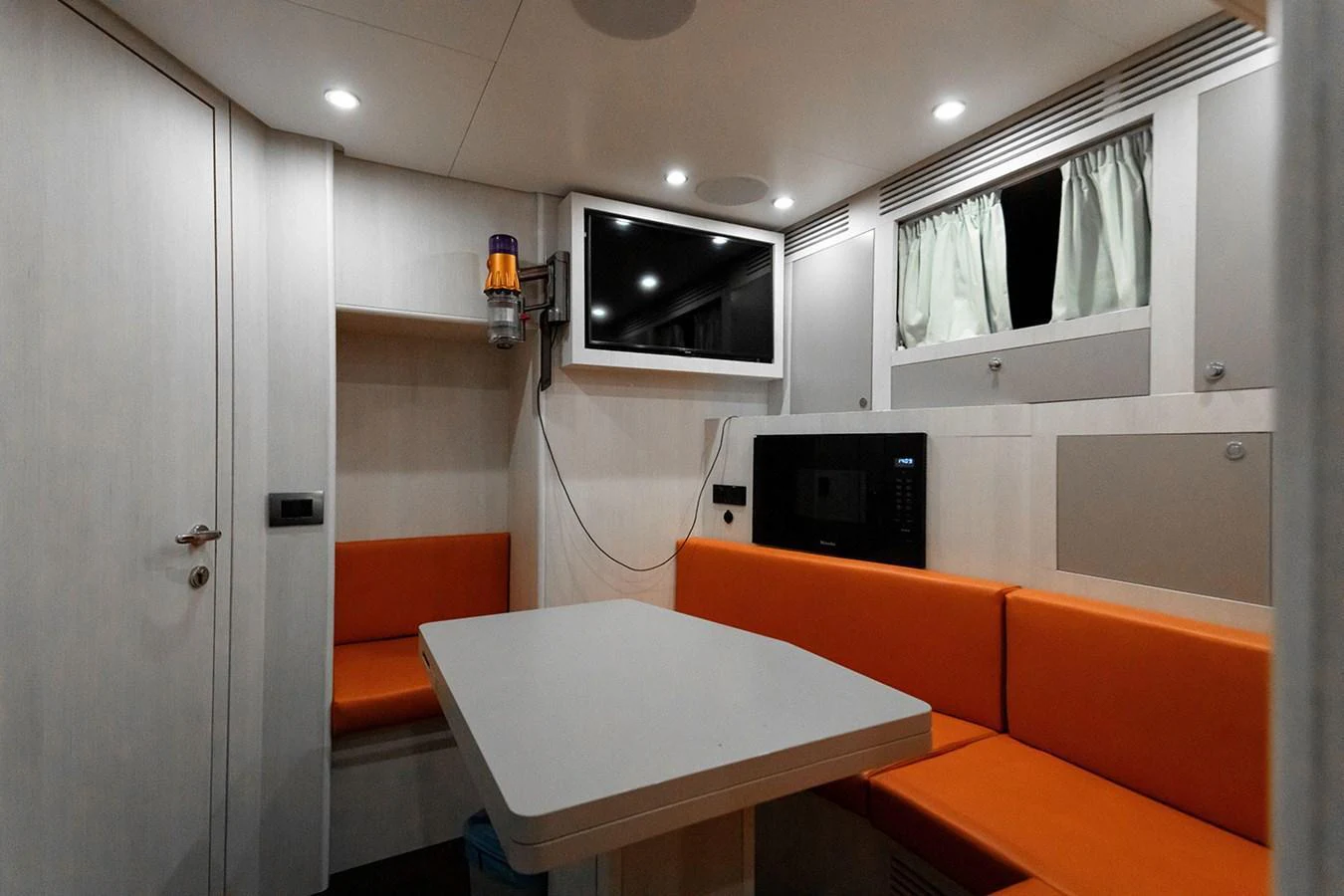 The crew mess area features a cozy dining space with vibrant orange seating and modern amenities. aboard TAMANYA Yacht for Sale