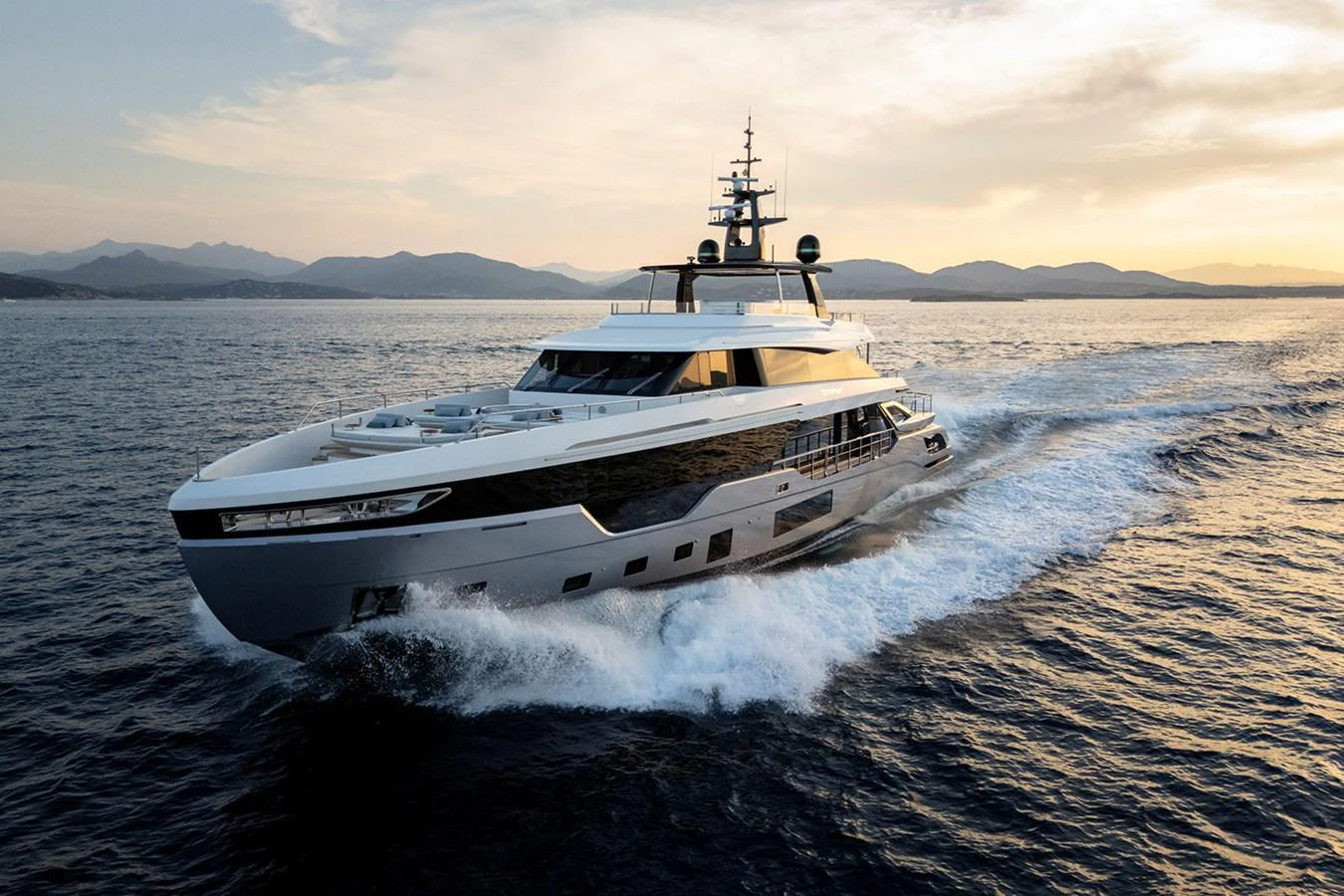 A sleek and modern yacht cruises through the open water at sunset. aboard TAMANYA Yacht for Sale