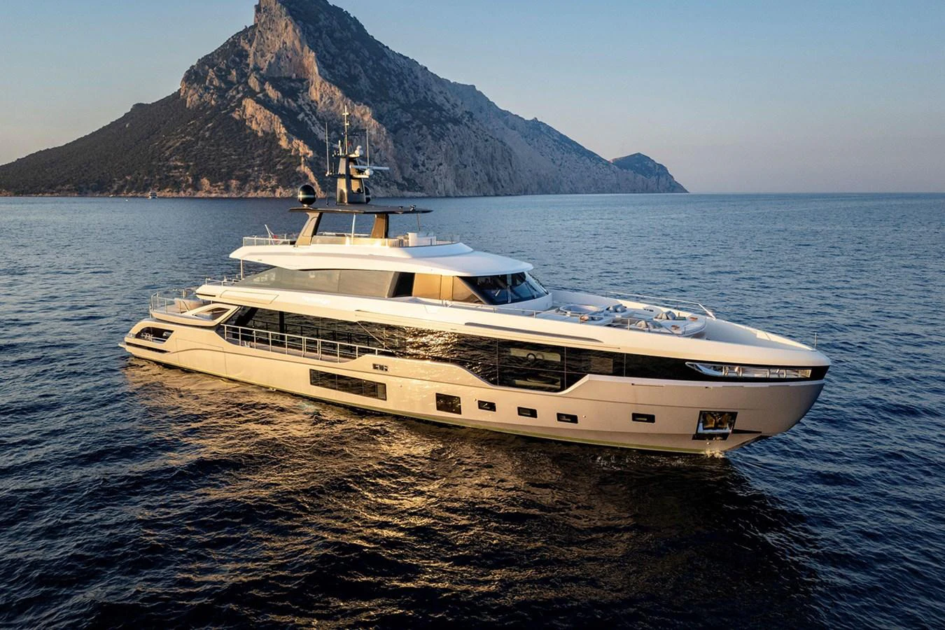 A luxurious yacht cruises gracefully on calm waters with a scenic mountainous backdrop. aboard TAMANYA Yacht for Sale