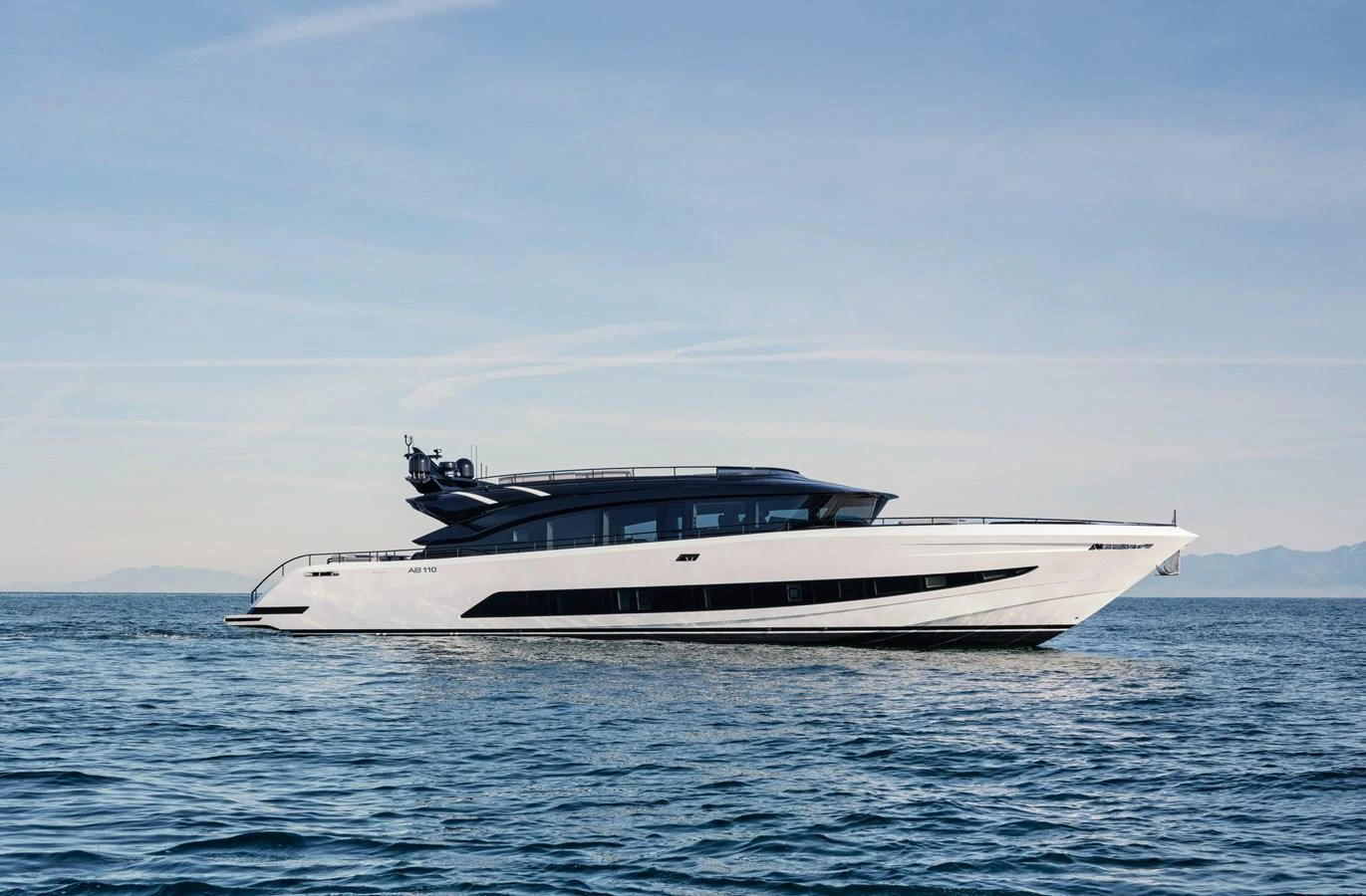 A sleek and modern yacht glides gracefully on calm waters under a clear sky. aboard AB 110 Yacht for Sale