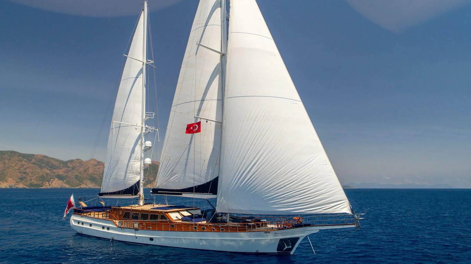 A stunning sailing yacht glides gracefully on the open sea under clear blue skies. aboard VOYAGE Yacht for Sale
