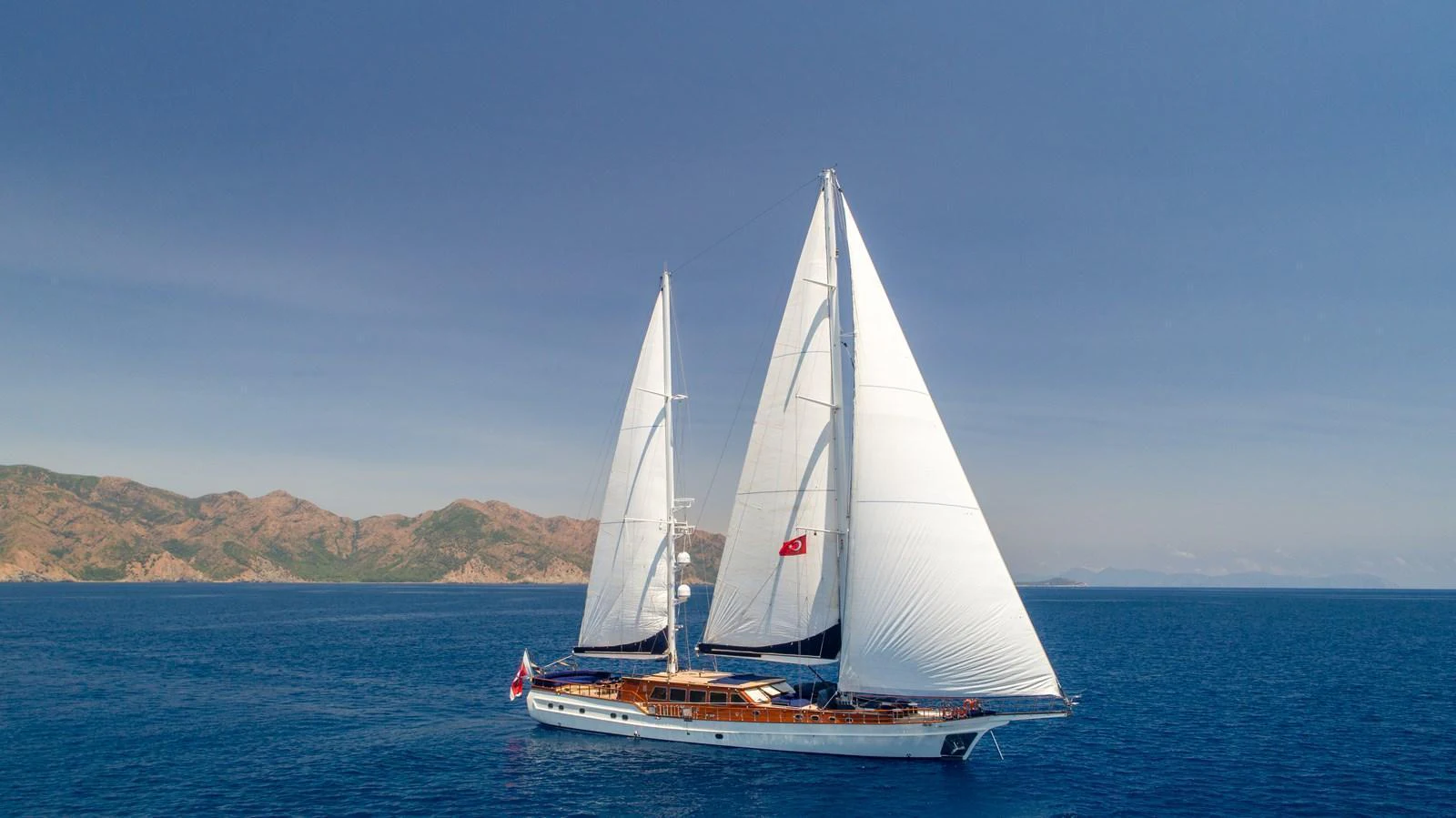 A stunning sailing yacht glides gracefully across the open sea under clear blue skies. aboard VOYAGE Yacht for Sale