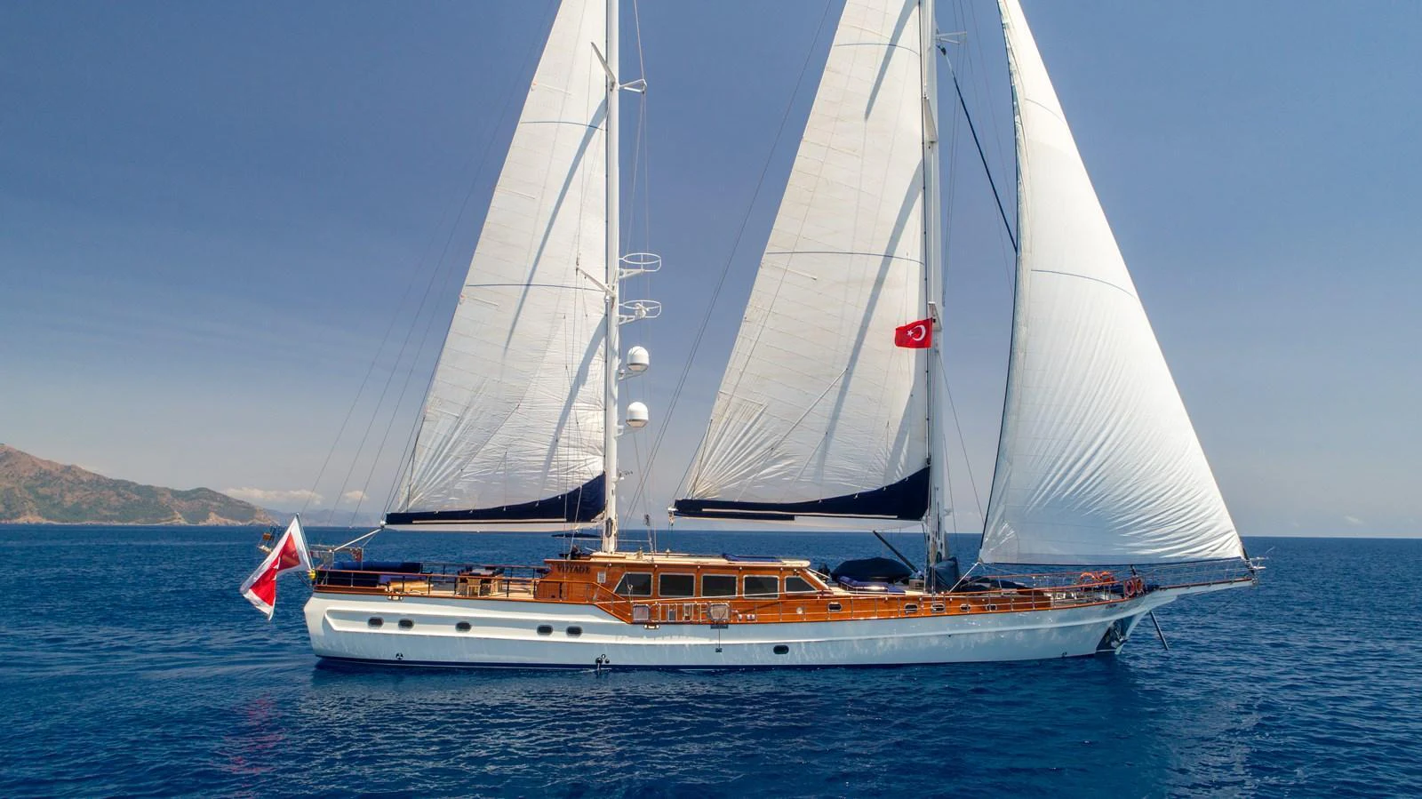 A stunning sailing yacht glides gracefully on the open sea under full sail. aboard VOYAGE Yacht for Sale