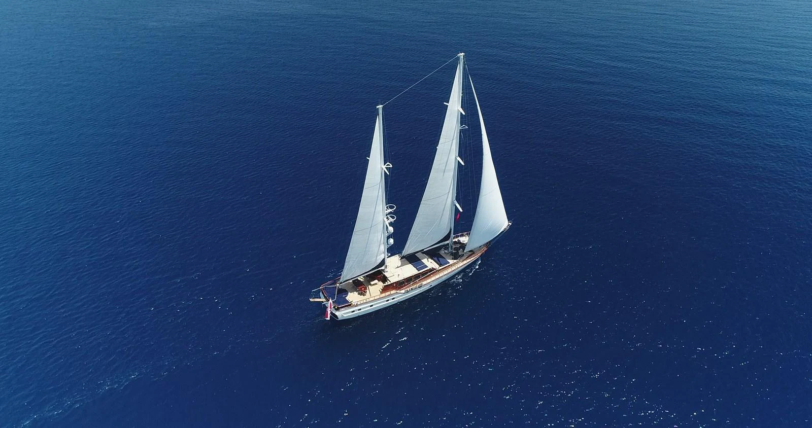 A stunning sailing yacht glides gracefully over the deep blue sea. aboard VOYAGE Yacht for Sale