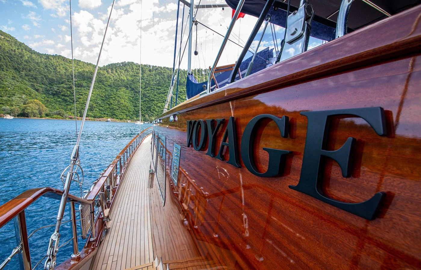 The yacht's polished wooden deck and sleek exterior reflect the surrounding natural beauty. aboard VOYAGE Yacht for Sale
