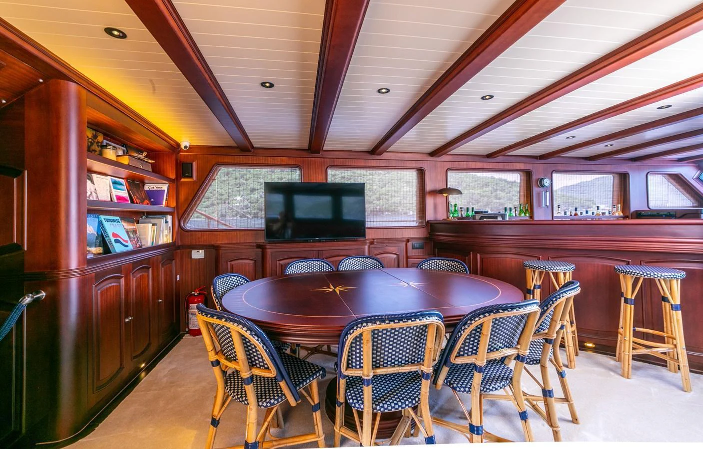 The yacht's interior dining area features a large round table surrounded by comfortable chairs and a well-stocked bar. aboard VOYAGE Yacht for Sale