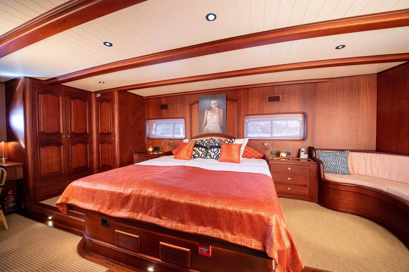 The master stateroom features luxurious wood paneling, a large bed with vibrant bedding, and elegant lighting. aboard VOYAGE Yacht for Sale