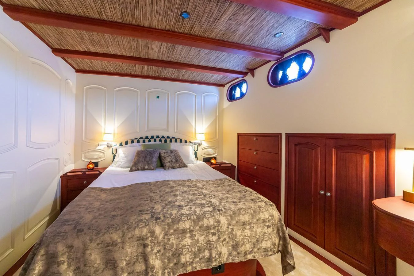 A cozy stateroom with a double bed and warm wooden accents. aboard VOYAGE Yacht for Sale