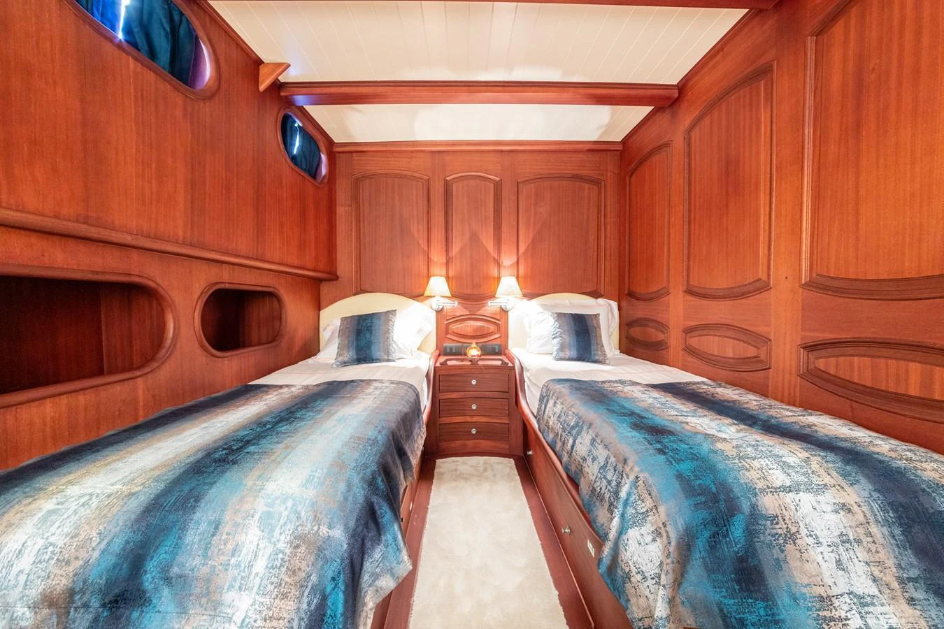 The twin stateroom features elegant wood paneling and comfortable bedding for a cozy retreat. aboard VOYAGE Yacht for Sale